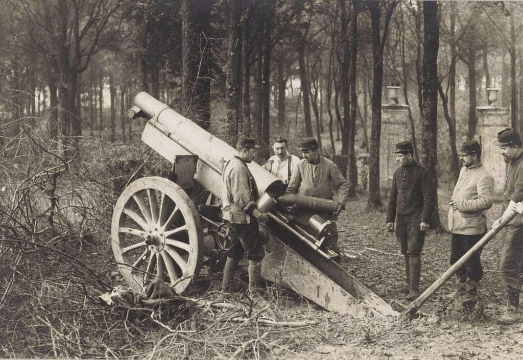 Servants français chargeant un canon de 75 en forêt, 1914