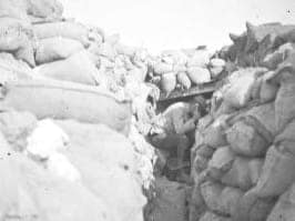 Téléphoniste français au fond d'une tranchée bordée de sacs de sable, réglant le tir d'artillerie pendant le bombardement des tranchées allemandes pendant la Première Guerre mondiale.