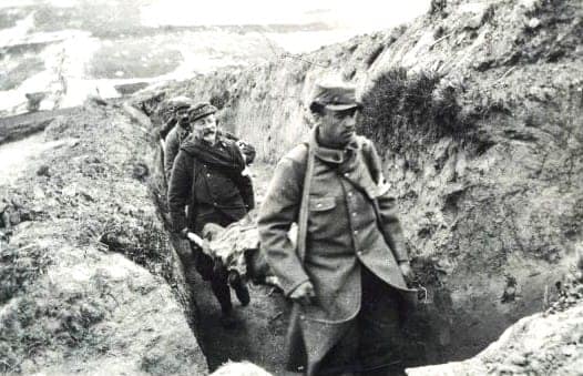 Brancardiers Grande Guerre du clergé évacuant un blessé sur brancard dans un boyau de tranchée en mai 1915