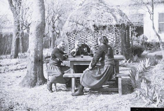 Trois zouaves du 3ᵉ Régiment de Zouaves attablés dans un jardin, uniforme traditionnel à pantalon bouffant et chéchia, Première Guerre mondiale